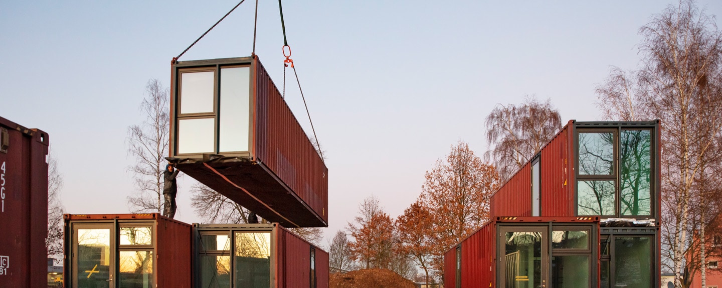 Containermodul wird per Kran auf der Baustelle montiert